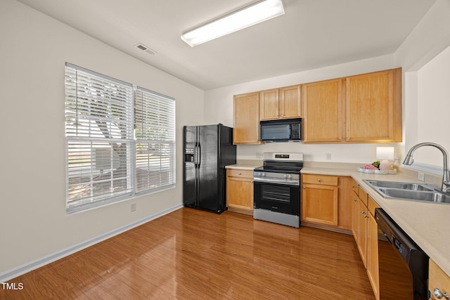 8151 Rhiannon Rd, Raleigh, NC 27613 - kitchen with black appliances, light wood-style floors, light countertops, and light brown cabinets