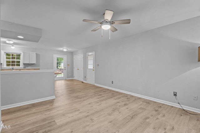 627 Gaslight Trl, Wendell, NC 27591 - unfurnished living room featuring baseboards, light wood-style floors, ceiling fan, and a sink