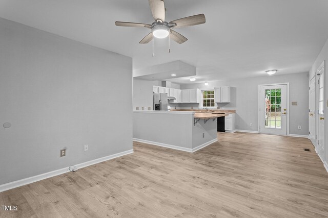 627 Gaslight Trl, Wendell, NC 27591 - kitchen with stainless steel fridge with ice dispenser, light wood-style floors, a peninsula, a ceiling fan, and white cabinets