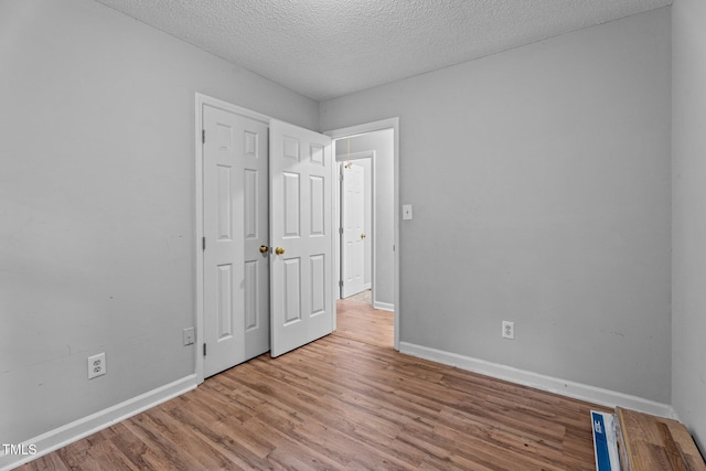 627 Gaslight Trl, Wendell, NC 27591 - unfurnished bedroom featuring wood finished floors, baseboards, a textured ceiling, and a closet