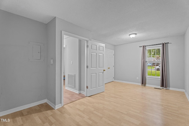 627 Gaslight Trl, Wendell, NC 27591 - spare room with light wood-type flooring, electric panel, a textured ceiling, and baseboards
