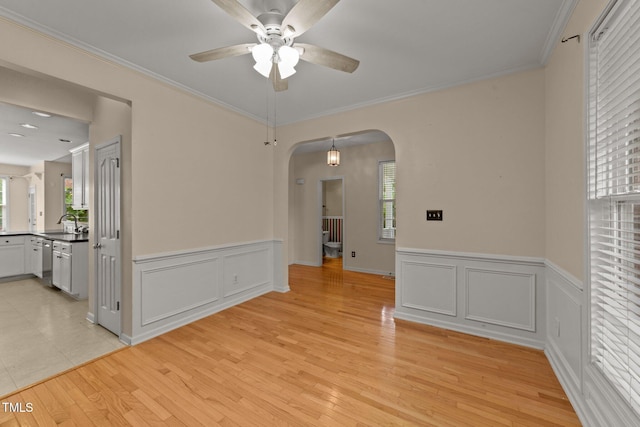 1604 Carnation Dr, Durham, NC 27703 - unfurnished room with ceiling fan, arched walkways, a wainscoted wall, light wood-type flooring, and crown molding