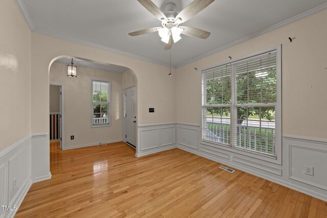 1604 Carnation Dr, Durham, NC 27703 - unfurnished room with arched walkways, a wainscoted wall, light wood-type flooring, a ceiling fan, and crown molding