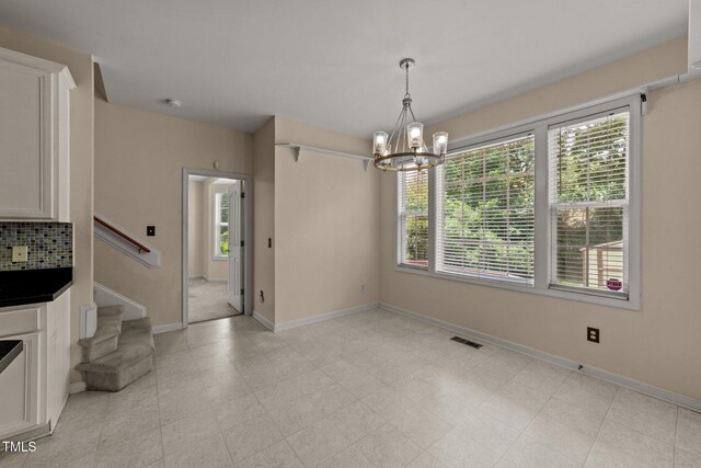 1604 Carnation Dr, Durham, NC 27703 - unfurnished dining area featuring a chandelier, stairs, and baseboards