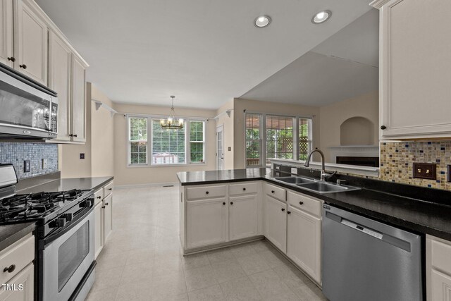 1604 Carnation Dr, Durham, NC 27703 - kitchen featuring stainless steel appliances, a sink, a chandelier, dark countertops, and tasteful backsplash