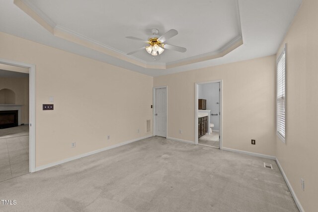 1604 Carnation Dr, Durham, NC 27703 - empty room featuring a fireplace, a raised ceiling, a ceiling fan, light carpet, and crown molding