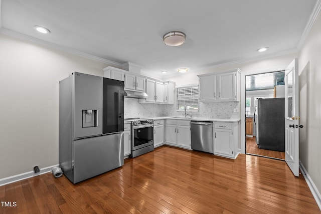 301 Williamson St, Burlington, NC 27215 - kitchen featuring stainless steel appliances, under cabinet range hood, light countertops, dark wood-style flooring, and ornamental molding