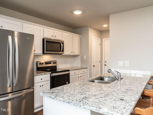 286 Beaver Tavern Dr, Benson, NC 27504 - kitchen with appliances with stainless steel finishes, a sink, a breakfast bar, white cabinetry, and light stone counters