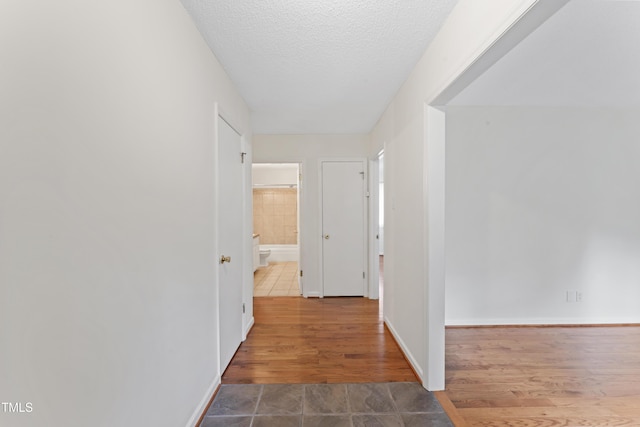 6411 Pondview Ln, Durham, NC 27712 - corridor featuring a textured ceiling, tile patterned flooring, and baseboards