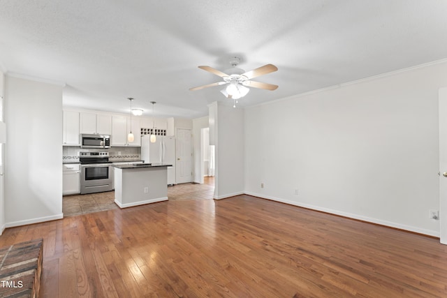 6411 Pondview Ln, Durham, NC 27712 - kitchen featuring stainless steel appliances, open floor plan, ceiling fan, wood-type flooring, and baseboards