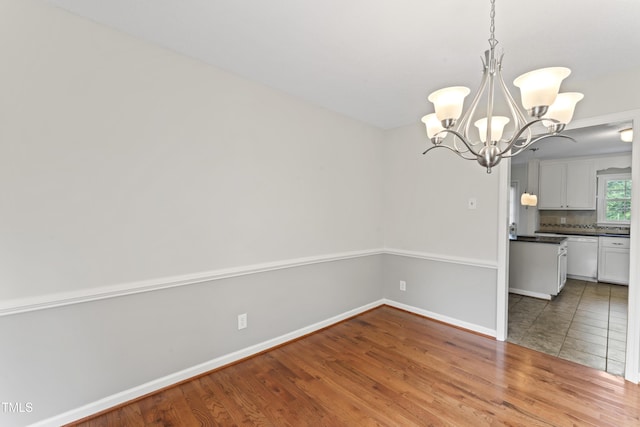 6411 Pondview Ln, Durham, NC 27712 - unfurnished dining area featuring a chandelier, wood finished floors, and baseboards