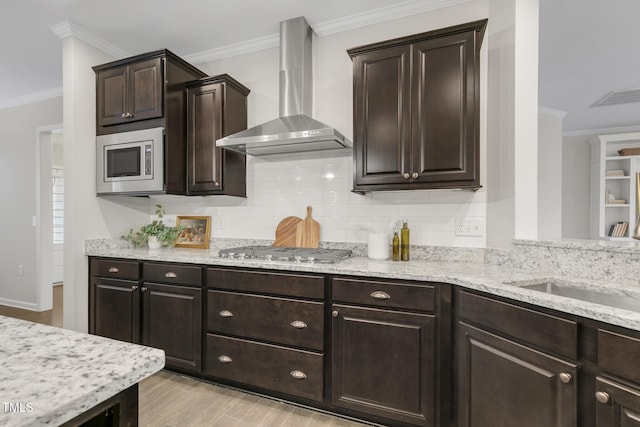 118 Manning Way, Durham, NC 27703 - kitchen featuring wall chimney range hood, appliances with stainless steel finishes, ornamental molding, dark brown cabinetry, and light stone countertops