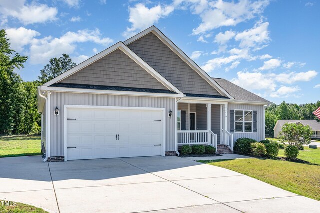 41 Tan Oak Dr, Selma, NC 27576 - view of front facade featuring covered porch, driveway, a front lawn, a garage, and board and batten siding