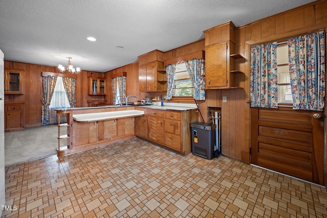 4804 Spring Forest Rd, Raleigh, NC 27616 - kitchen with open shelves, a peninsula, brown cabinetry, wood walls, and a chandelier