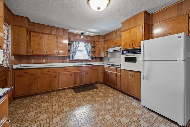 4804 Spring Forest Rd, Raleigh, NC 27616 - kitchen featuring white appliances, under cabinet range hood, brown cabinets, a textured ceiling, and light countertops
