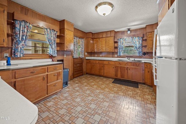 4804 Spring Forest Rd, Raleigh, NC 27616 - kitchen with freestanding refrigerator, open shelves, wood walls, light countertops, and brown cabinetry