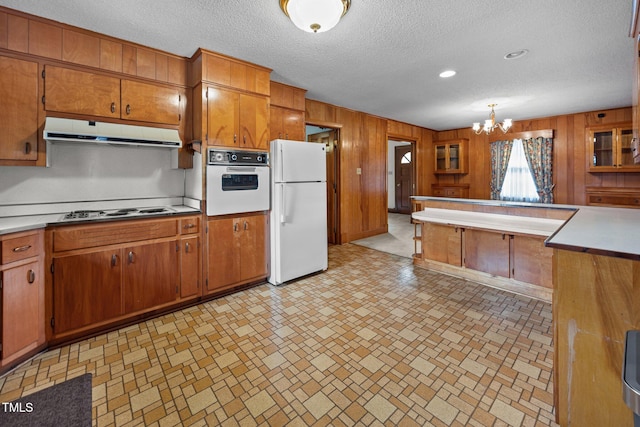 4804 Spring Forest Rd, Raleigh, NC 27616 - kitchen with white appliances, ventilation hood, brown cabinetry, wood walls, and light countertops