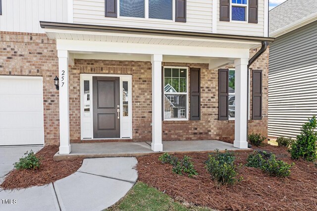 257 N Maple Walk Dr Unit 218, Garner, NC 27529 - doorway to property with a porch, brick siding, and a garage
