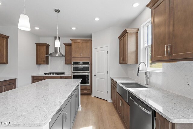 257 N Maple Walk Dr Unit 218, Garner, NC 27529 - kitchen with wall chimney exhaust hood, appliances with stainless steel finishes, a sink, light wood-style floors, and backsplash