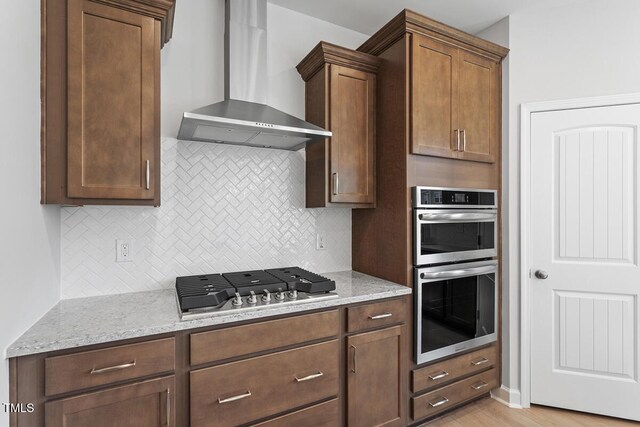 257 N Maple Walk Dr Unit 218, Garner, NC 27529 - kitchen with wall chimney exhaust hood, appliances with stainless steel finishes, backsplash, and light stone countertops