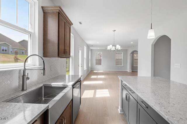 257 N Maple Walk Dr Unit 218, Garner, NC 27529 - kitchen with a sink, dishwasher, arched walkways, backsplash, and light wood-style flooring