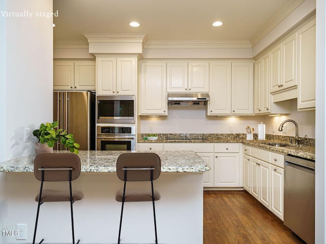 3339 Ridgecrest Ct, Raleigh, NC 27607 - kitchen with appliances with stainless steel finishes, under cabinet range hood, a kitchen bar, crown molding, and light stone countertops