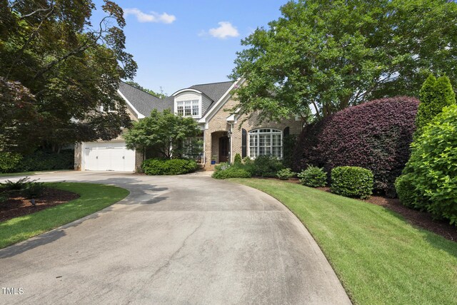 1210 Brooks Ave, Raleigh, NC 27607 - traditional-style house with brick siding, curved driveway, a front yard, and a garage
