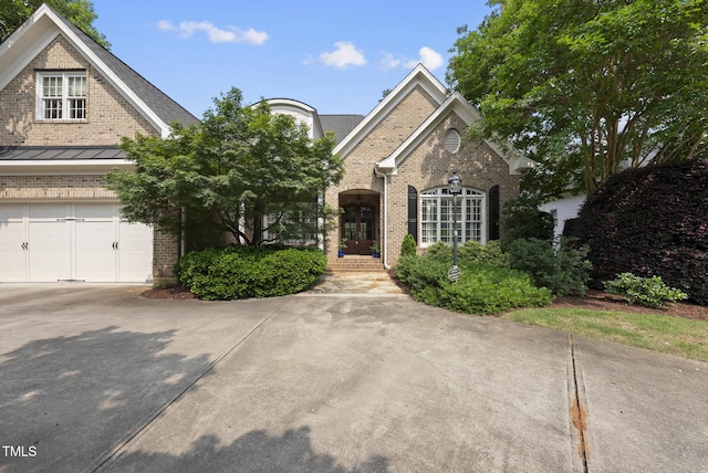 1210 Brooks Ave, Raleigh, NC 27607 - traditional-style house with brick siding, a garage, concrete driveway, a standing seam roof, and french doors