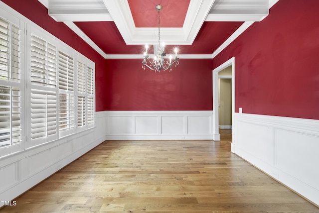 1210 Brooks Ave, Raleigh, NC 27607 - unfurnished dining area featuring a chandelier, a raised ceiling, wood finished floors, a wainscoted wall, and ornamental molding