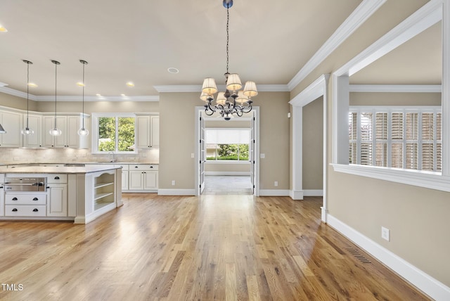 1210 Brooks Ave, Raleigh, NC 27607 - kitchen with a sink, a chandelier, light countertops, white cabinetry, and decorative backsplash