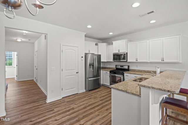 1728 Shady Oaks Dr, Wendell, NC 27591 - kitchen featuring appliances with stainless steel finishes, a sink, dark wood finished floors, white cabinetry, and ornamental molding