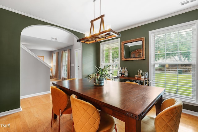 202 Stonecreek Dr, Apex, NC 27539 - dining space with arched walkways, ornamental molding, baseboards, light wood-style floors, and a chandelier