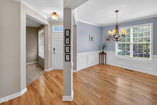 1437 Lindenberg Sq, Wake Forest, NC 27587 - foyer featuring light wood-style floors, a chandelier, crown molding, and a wainscoted wall