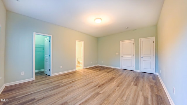 151 Braeside Ct, Cary, NC 27519 - unfurnished bedroom with light wood-style flooring, baseboards, a closet, a walk in closet, and connected bathroom