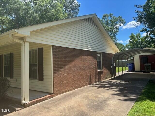 708 Old Barn Ave, Durham, NC 27704 - view of side of home with brick siding, a detached carport, and driveway