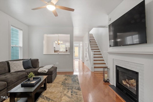 4605 All Points View Way, Raleigh, NC 27614 - living area featuring wood finished floors, a chandelier, a ceiling fan, a brick fireplace, and stairs