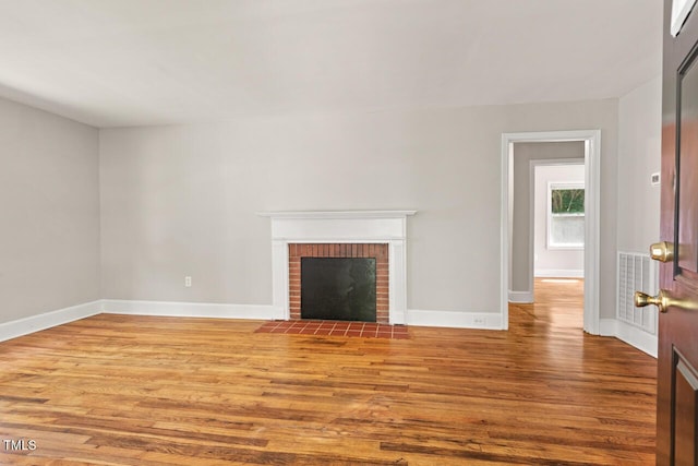 1411 Hudson Ave, Durham, NC 27705 - unfurnished living room with wood finished floors, baseboards, and a brick fireplace