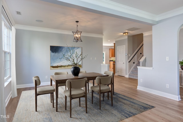 12320 Tetons Ct, Durham, NC 27703 - dining space featuring stairs, light wood finished floors, arched walkways, crown molding, and a chandelier