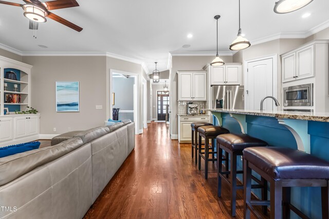2538 Tuffeto, Apex, NC 27502 - kitchen with stainless steel appliances, a kitchen bar, light stone counters, dark wood-style flooring, and a ceiling fan