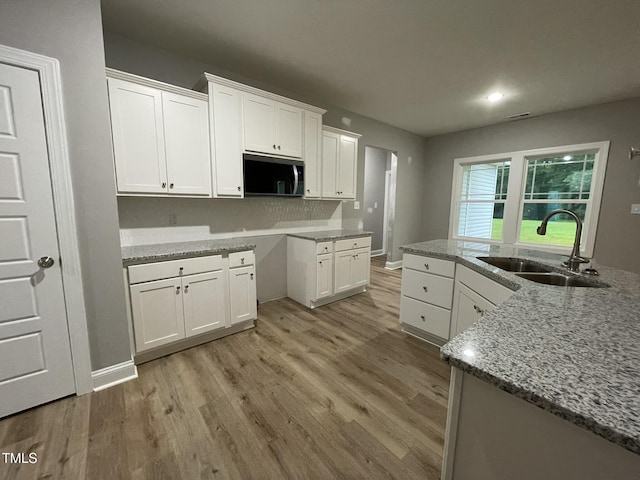 268 Busterfield Ct, Benson, NC 27504 - kitchen featuring a sink, stainless steel microwave, light wood-style flooring, white cabinetry, and recessed lighting