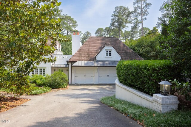 3307 Devon Rd, Durham, NC 27707 - view of front of property with asphalt driveway, a garage, a chimney, a standing seam roof, and metal roof