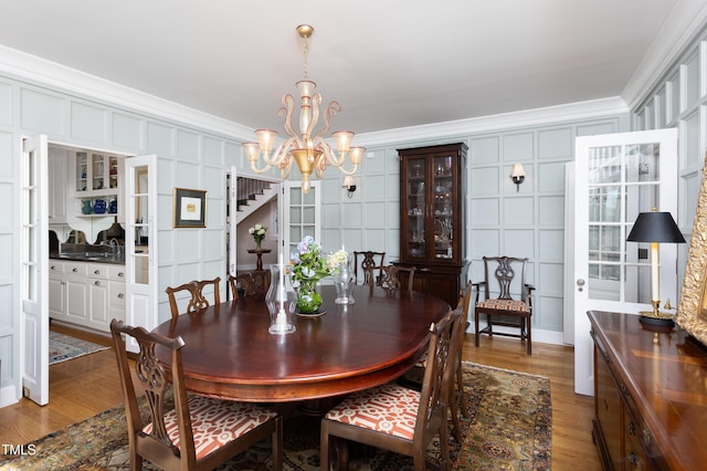 3307 Devon Rd, Durham, NC 27707 - dining space featuring crown molding, a chandelier, light wood-style flooring, and a decorative wall
