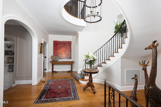 3307 Devon Rd, Durham, NC 27707 - foyer with wood finished floors, a chandelier, arched walkways, baseboards, and stairs
