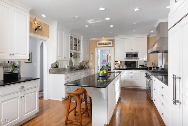 3307 Devon Rd, Durham, NC 27707 - kitchen with appliances with stainless steel finishes, white cabinetry, a sink, a center island, and light wood-style flooring