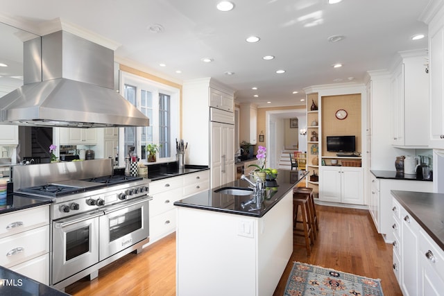 3307 Devon Rd, Durham, NC 27707 - kitchen with high end appliances, wall chimney exhaust hood, a sink, dark countertops, and ornamental molding