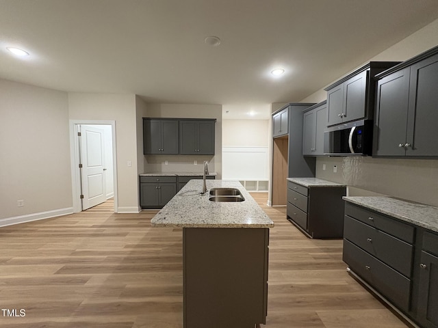 78 Mineral Springs Way, Benson, NC 27504 - kitchen featuring light stone countertops, an island with sink, stainless steel microwave, light wood-style flooring, and recessed lighting