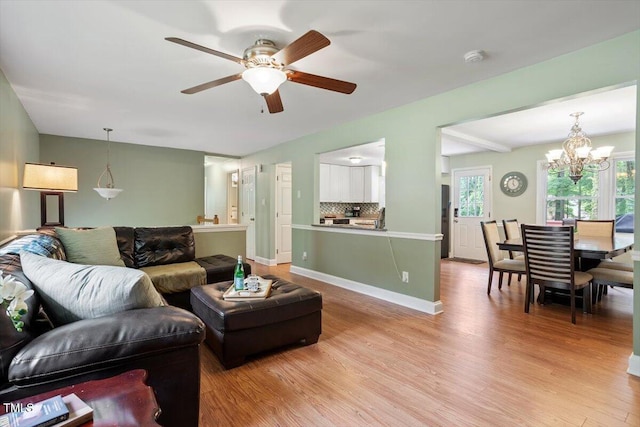 1109 Buckingham Rd, Garner, NC 27529 - living room featuring light wood-type flooring, a ceiling fan, a chandelier, and baseboards