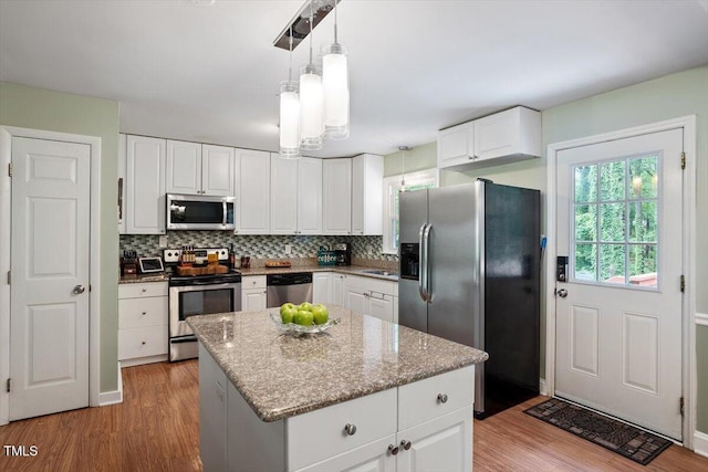 1109 Buckingham Rd, Garner, NC 27529 - kitchen with stainless steel appliances, a sink, light wood-style floors, decorative backsplash, and white cabinets