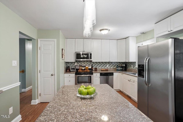 1109 Buckingham Rd, Garner, NC 27529 - kitchen featuring appliances with stainless steel finishes, wood finished floors, white cabinets, tasteful backsplash, and baseboards