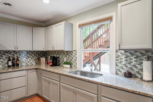 1109 Buckingham Rd, Garner, NC 27529 - kitchen featuring a sink, ornamental molding, backsplash, and light stone countertops